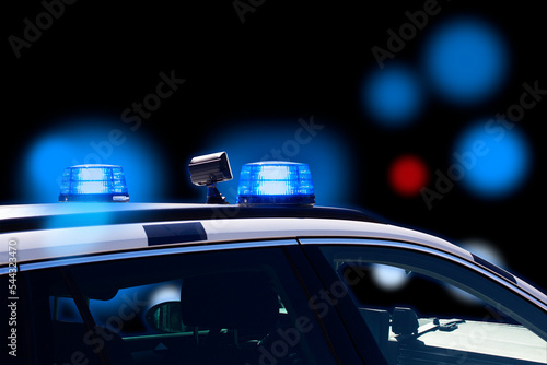 Police car at night with flashing lights and blurred bokeh blue and red lights on black background. Copy space.