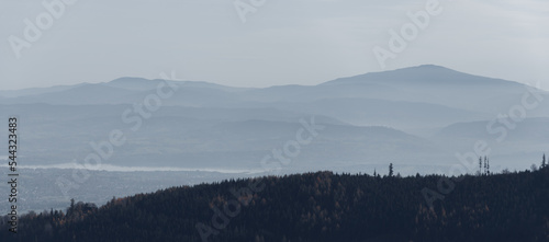 Fototapeta Naklejka Na Ścianę i Meble -  Panoramic view on Beskidy Mountains. Hills covered with forest in the morning fog. Babia Gora in the background. Zywieckie Lake and city in the valley.