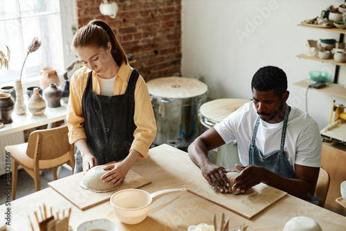 High angle portrait of two people making handmade ceramics in cozy pottery studio, copy space
