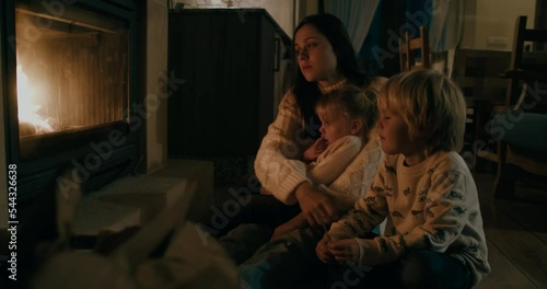 European family sit in front of fireplace on winter evening at vacation