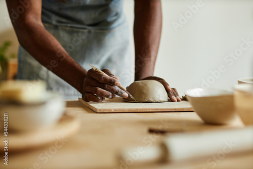 Close up of male artist creating handmade ceramic bowl in cozy pottery studio, copy space