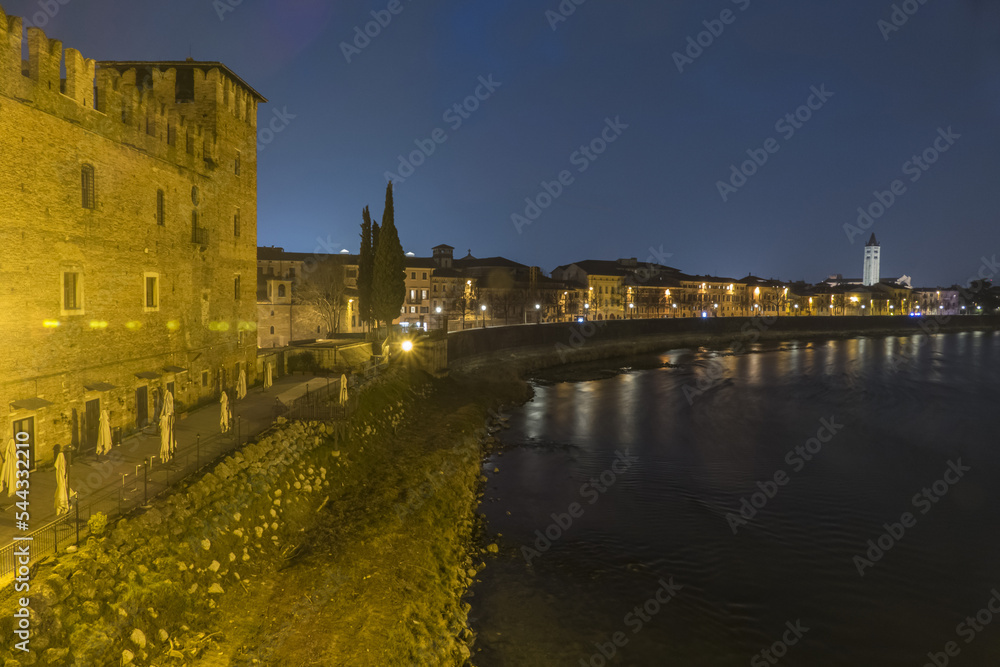 The Adige river and the panorama of Verona seen from the Castelvecchio bridge illuminated at night