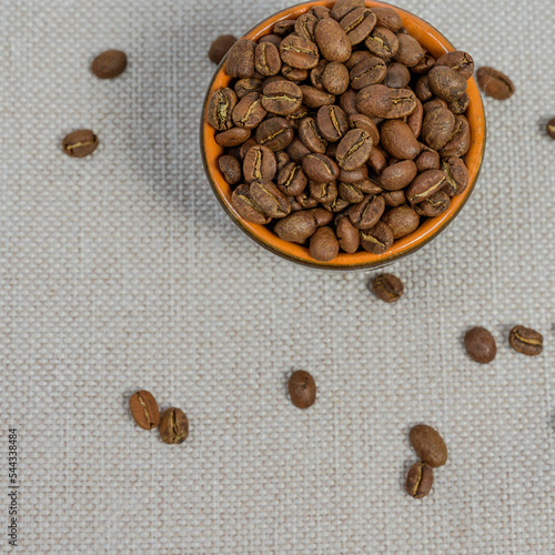 Fototapeta Naklejka Na Ścianę i Meble -  A cup with coffee beans on the background, spilled coffee beans near the cup.