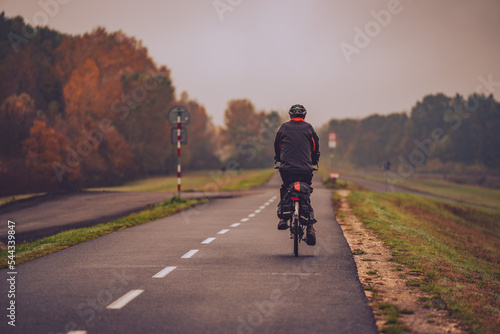 Person riding a bicycle on a road in autumn