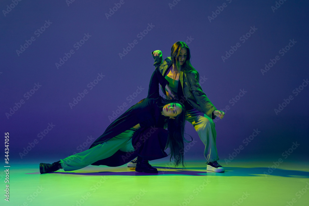 Two dancers, stylish fashionable dance couple dancing contemporary dance on colorful gradient blue-green background in neon light. Concept of art, creativity, movement, style and fashion, action. Two dancers, stylish fashionable dance couple dancing contemporary dance on colorful gradient blue-green background in neon light. Concept of art, creativity, movement, style and fashion, action.
