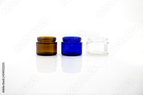 trzy małe kolorowe szklane pojemniki na kosmetyki na białym tle © Kamil_k2p
