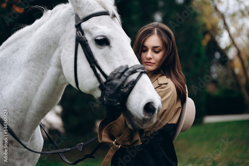 A young woman hugs a white horse.