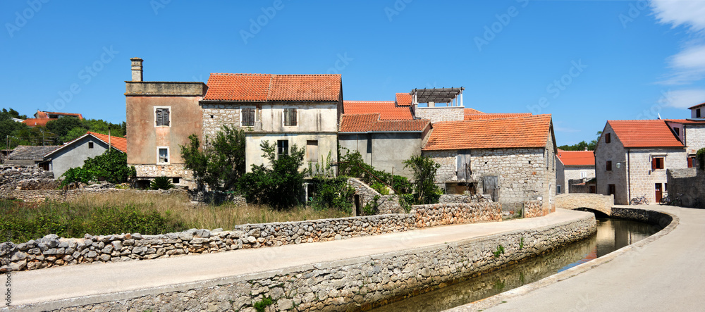 Stone bridge and old historic houses in Vrboska village, Hvar island, Dalmatia, Croatia, Europe. Panoramic banner image. Old fisherman village, famous tourist attraction.