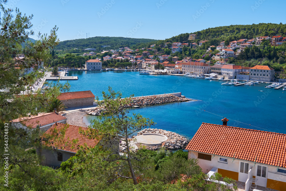 Jelsa, Hvar island in Croatia. Scenic summer day view of the city of Jelsa, bird view from hill. Jelsa bay, seaside buildings and local marina. Red roofs of traditional buildings.