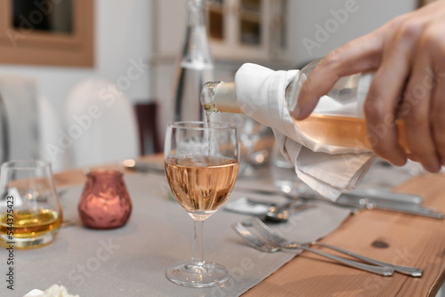 A waiter pours the pink french wine into the glass