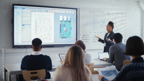 Black Female Teacher Using Digital Interactive Screen, Talks to Group of Diverse Students and Shows 3D Circuit Board Components. Education and University of Technology Concept.