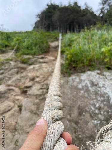 Male hand holds rope for climbing mountain slope at Cape Velikan, Sakhalin Island, Bottom view photo