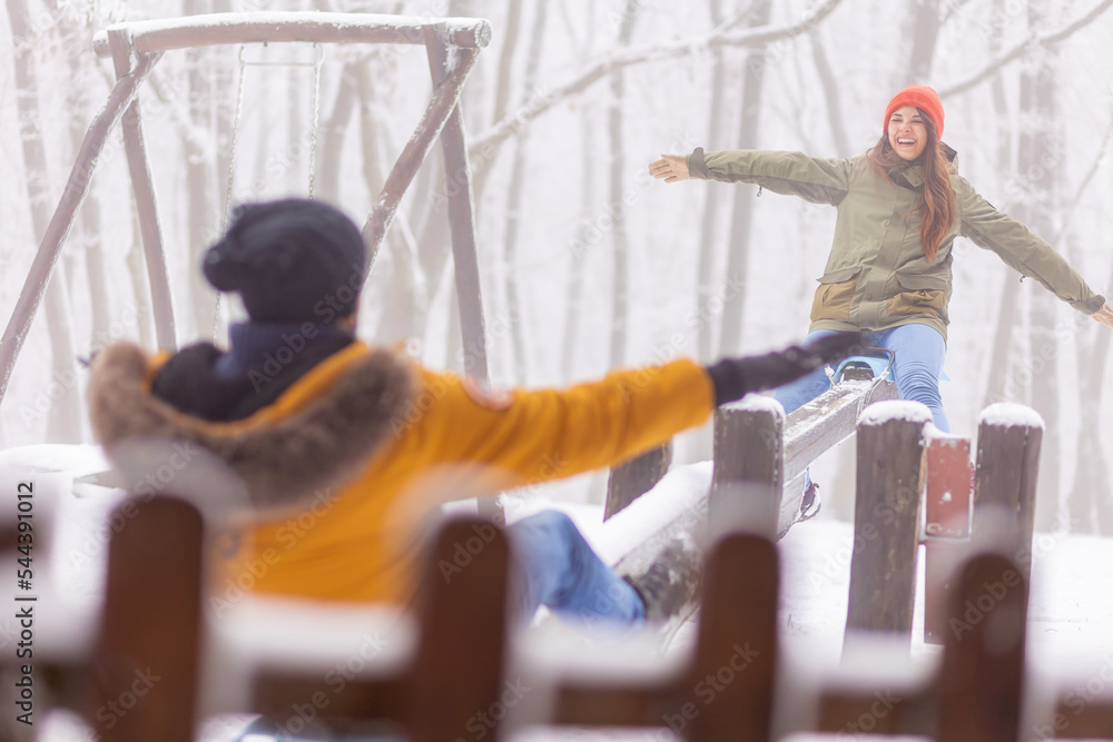 Couple having fun playing on seesaw while on winter vacation Couple having fun playing on seesaw while on winter vacation