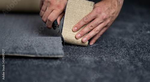 Fotografie Handyman cutting a new carpet with a carpet cutter...