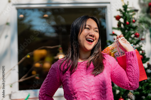 Happy smile asian woman standing behind Christmas tree, Holiday celebration concept.