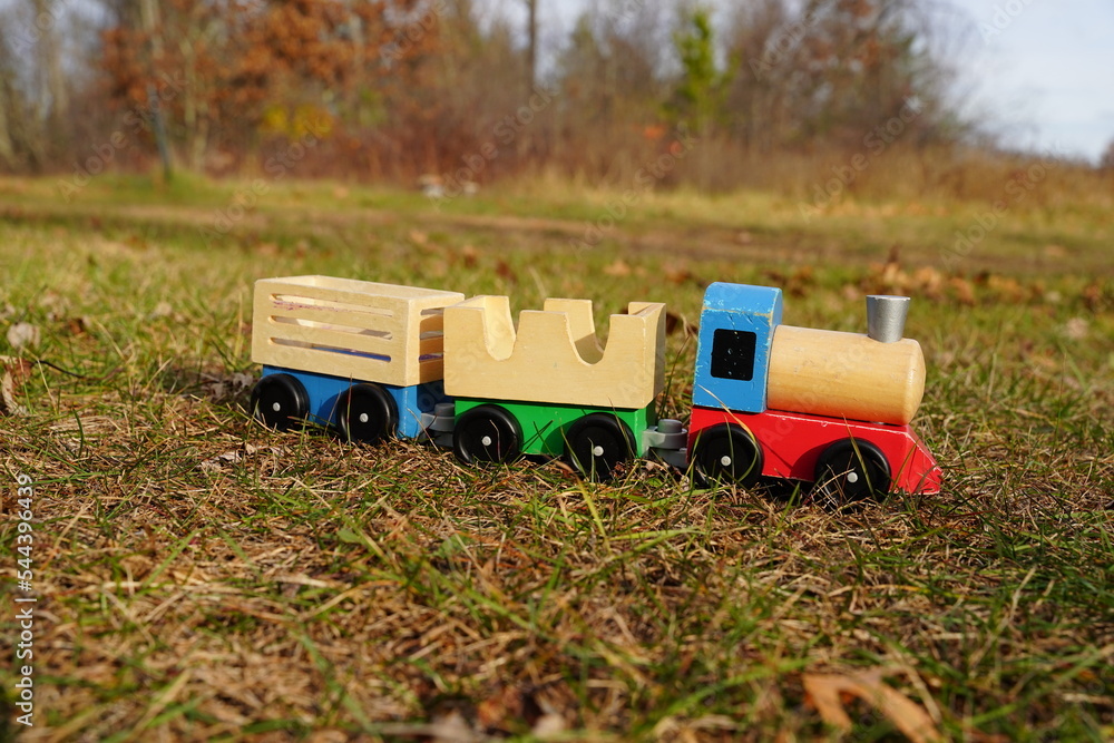 Children's wooden toy train sits outside.