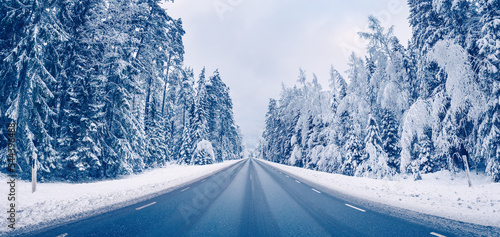 Empty asphalt road in snowy forest in winter