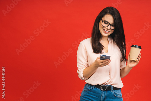 Photo of cheerful cute beautiful business young woman using mobile phone isolated over red background. Space for text.