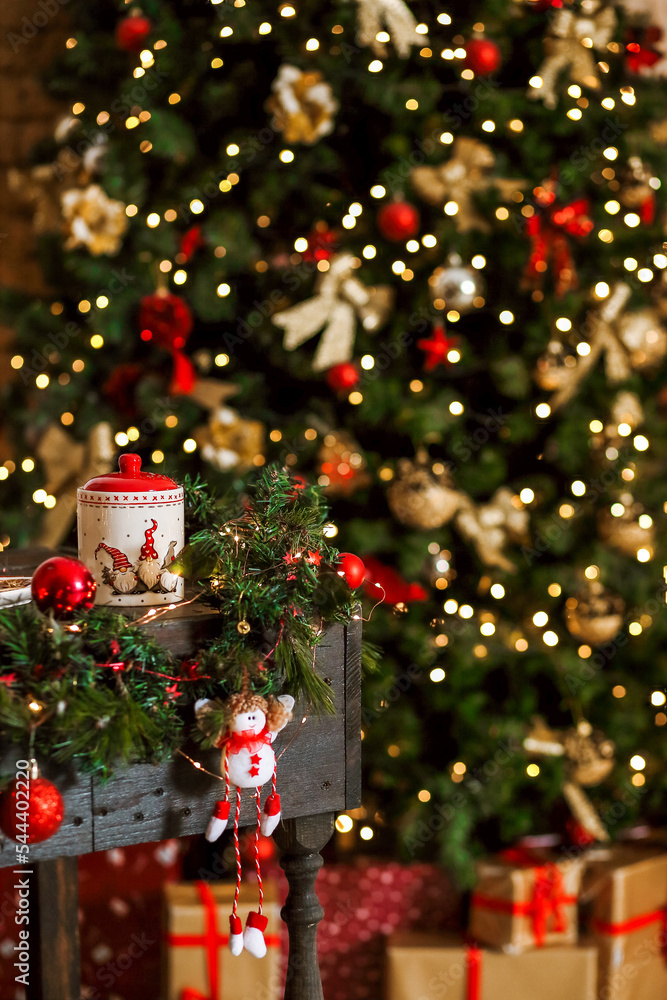 Christmas composition with a candy bowl and a red ball on the table against a background of blurred lights Christmas composition with a candy bowl and a red ball on the table against a background of blurred lights