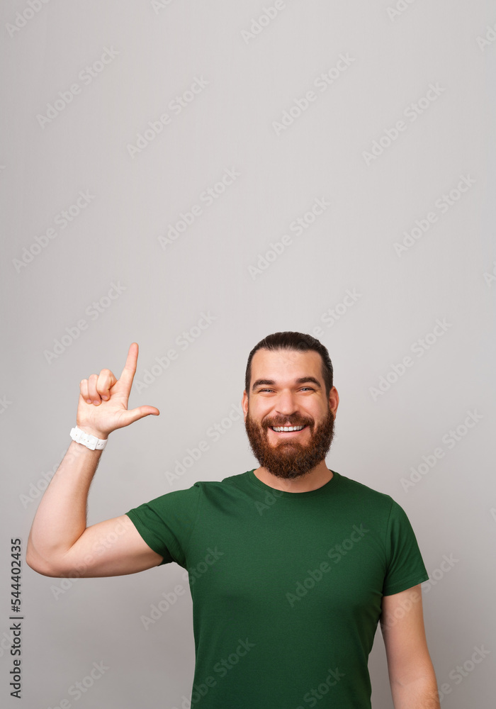 Fototapeta premium Vertical shot of a strong handsome man pointing up at the copy space above.