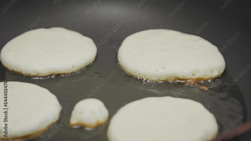 Pancakes are fried in oil on a hot old frying pan. Close-up. Cooking homemade pancakes for breakfast. Pancakes are fried in oil on a hot old frying pan. Close-up. Cooking homemade pancakes for breakfast.