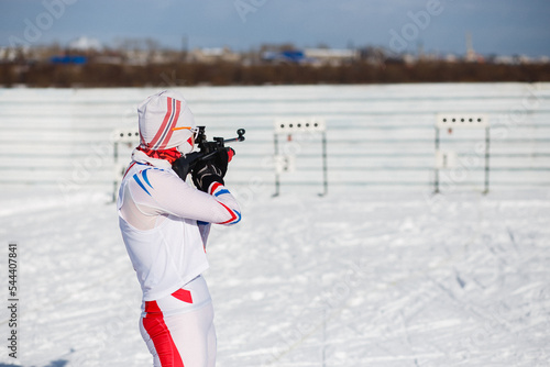 Fotografia Girl biathlete aims at a target at biathlon competitions