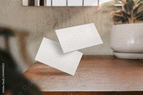 Clean minimal business card mockup on wood table with leaves foreground