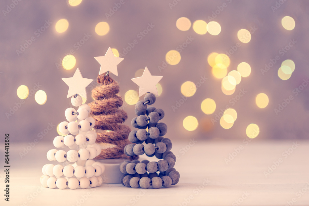 Obraz premium Three Christmas trees on table with bokeh lights.
