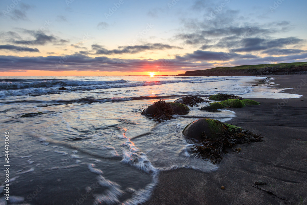 Stones covered with algae on the coast of the Atlantic Ocean at high tide at sunset