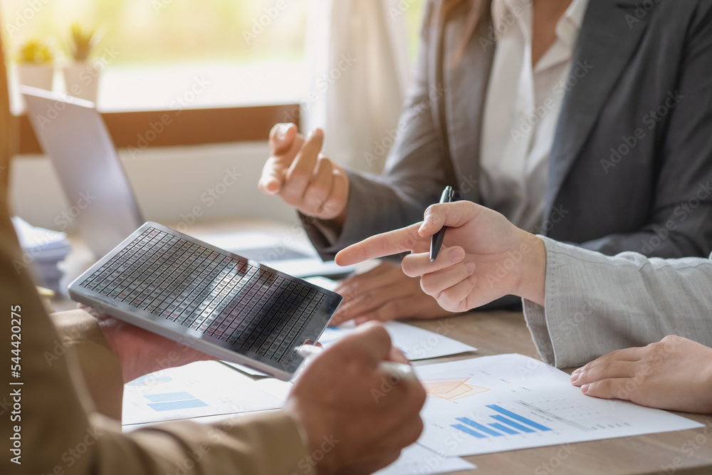 A team of businessmen plan with their laptops and graph charts for their profits and use a calculator to calculate their company is annual balance. A team of businessmen plan with their laptops and graph charts for their profits and use a calculator to calculate their company is annual balance.