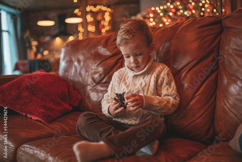 Foto Candid authentic happy little boy in knitted beige sweater fooling around at lod