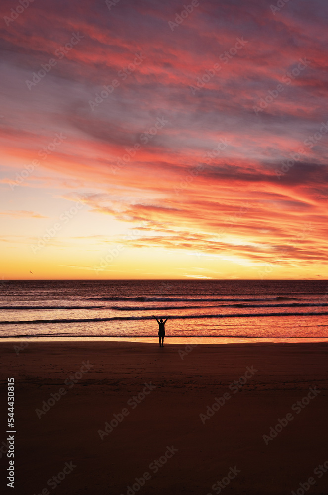 Naklejka premium Person with open arms at the beach during amazing sunrise