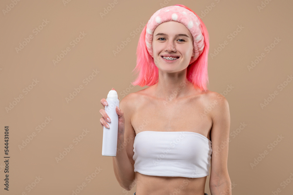 Young pinnk-haired girl holding a hair spray in hands Young pinnk-haired girl holding a hair spray in hands