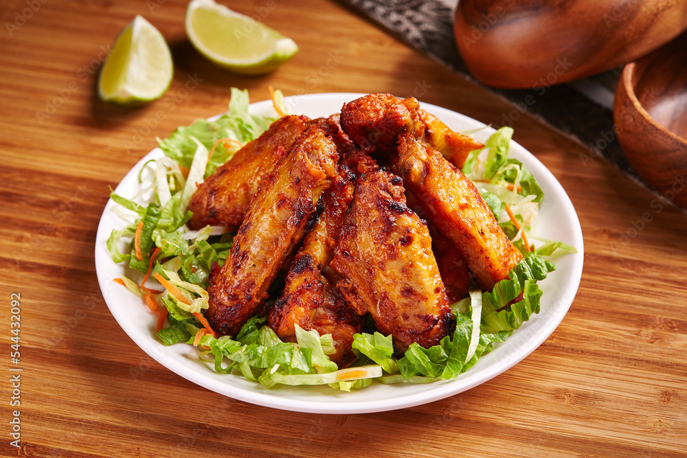 Spicy Grilled Chicken Wings with lemon and salad served in dish isolated on table side view of middle east food Spicy Grilled Chicken Wings with lemon and salad served in dish isolated on table side view of middle east food