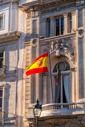 Spanish flag waving on a pole in a balcony of a classic building in Madrid