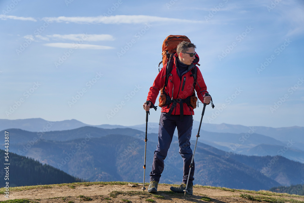 Young sporty hiker hiking in the mountains with his backpack on a bright sunny day. Picturesque mountain landscape.Concept of traveling in the mountains. Hiking in the mountains with a backpack       