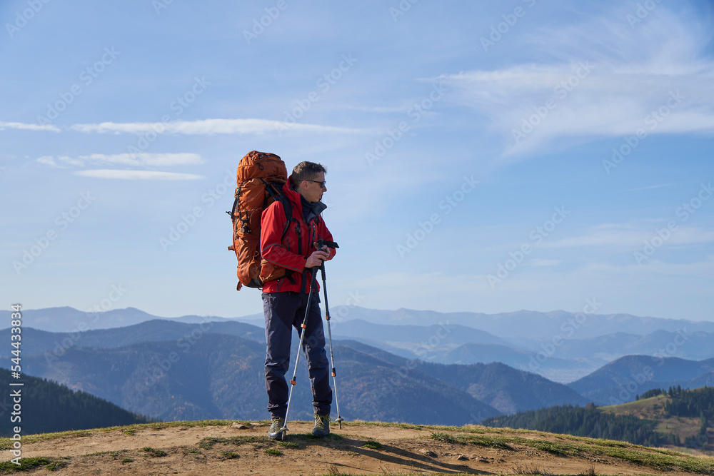 Young sporty hiker hiking in the mountains with his backpack on a bright sunny day. Picturesque mountain landscape.Concept of traveling in the mountains. Hiking in the mountains with a backpack       