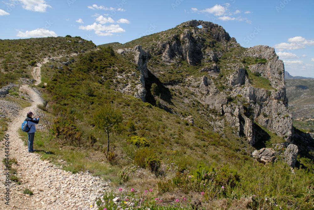 Woman hiker on mountain trail to the La Forada rock arch, Vall de Gallinera, Alicante Province, Spain