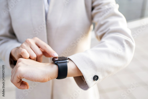 A smartwatch on a woman s hand touches the display with her finger.