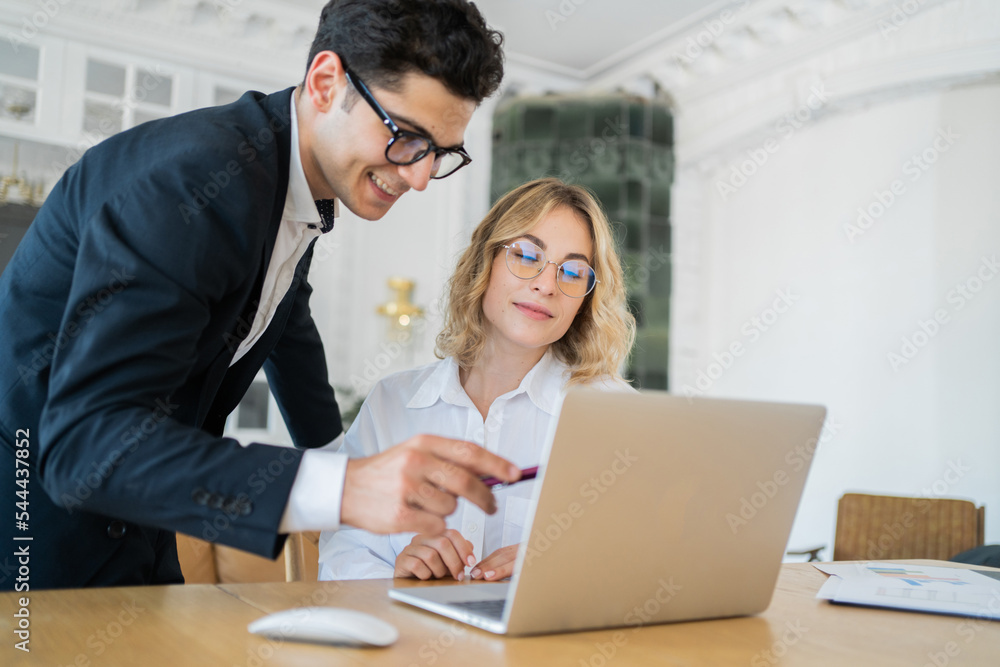 Male and female managers work together in the office on an online project.