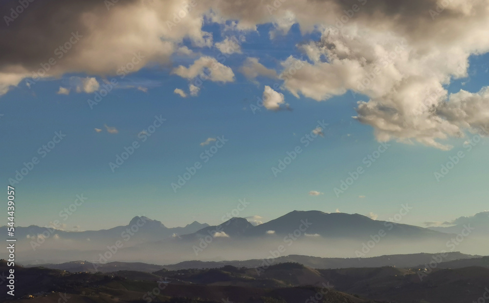 Nuvole bianche e nuvole nere nel cielo azzurro sopra i monti Appennini