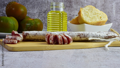 Fuet is a fine sausage from Catalonia, cured with pork meat. Accompanied by the contour of tomatoes, olive oil and bread.  photo