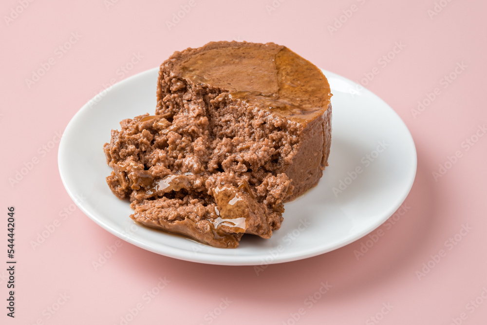 Soft pate for cat on a white plate over pastel pink background. Canned pet food of minced meat on a feeding plate closeup. Feed for carnivore domestic animals. Сat food concept.