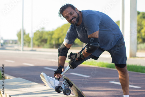 Portrait of bearded Caucasian man with skateboard. Mid adult sportsman in casual clothes and equipment looking at camera, smiling. Sport, lifestyle, training concept