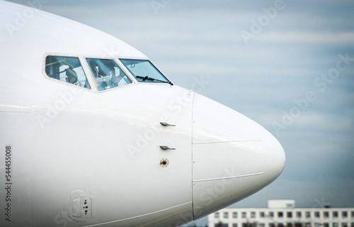 A modern passenger plane in white livery at the international airport on a cloudy morning.