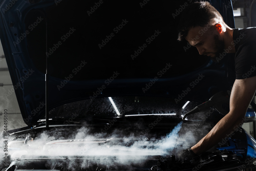 Obraz premium Steaming washing of motor of auto in detailing auto service. Process of steam cleaning car engine from dust and dirt.