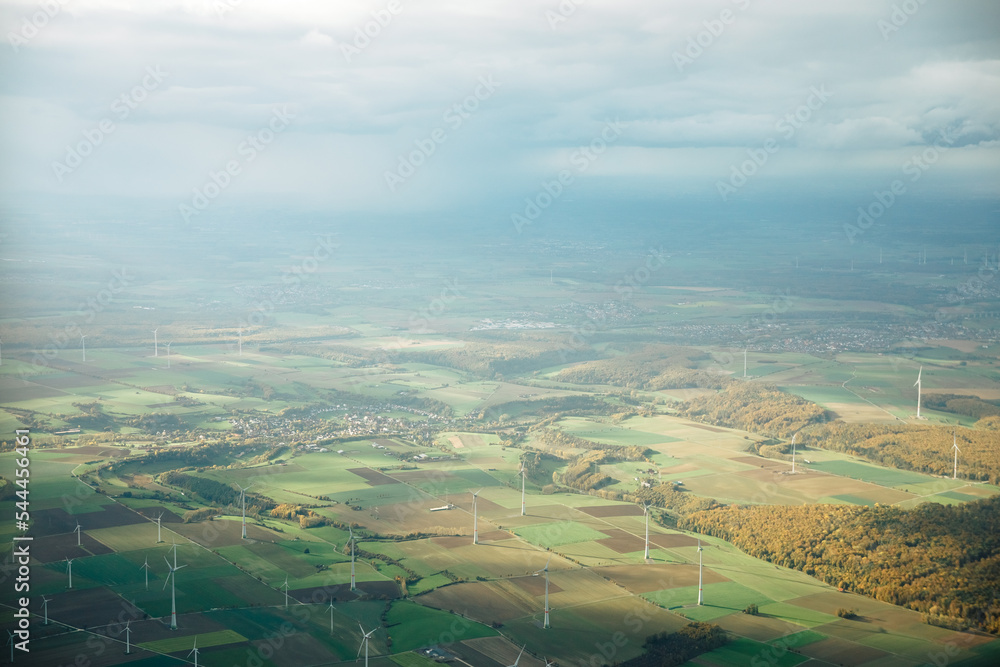 View from above on a German village, next to a forest with windmills. Wind turbines from above in summer in Germany