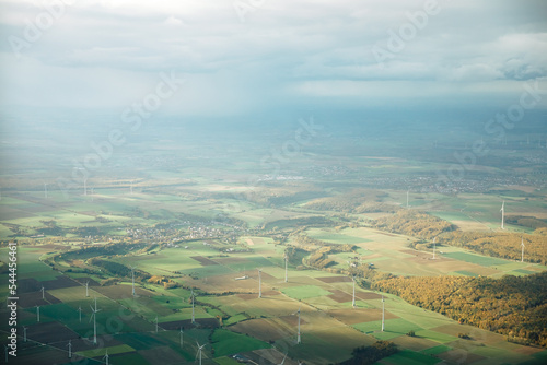 View from above on a German village, next to a forest with windmills. Wind turbines from above in summer in Germany