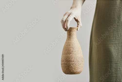 Minimal concept shot of female artist holding handmade ceramics, copy space photo