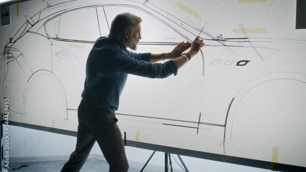 Mature automotive male designer creating sketch with duct tape on paper